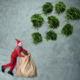 Ein weihnachtlich gekleideter Mann hält einen Sack auf wo Tannenbäume hinein fliegen