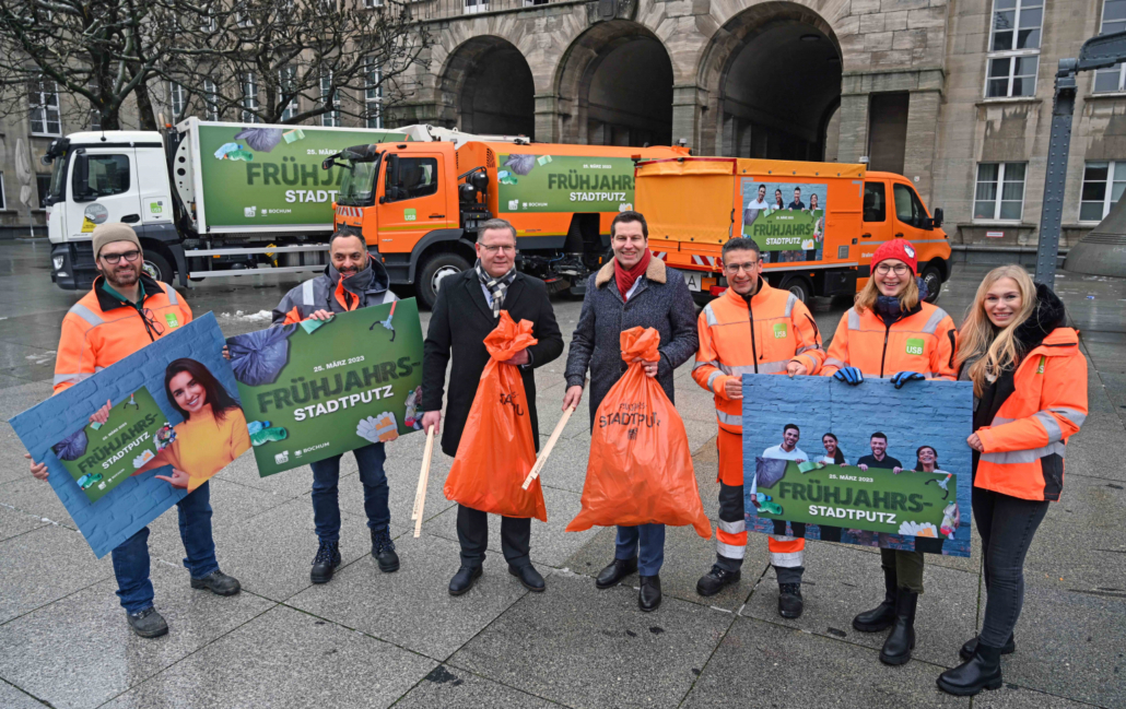 7 Personen stehen vor drei Fahrzeugen und halten stadtputzmaterial und Schilder in der Hand