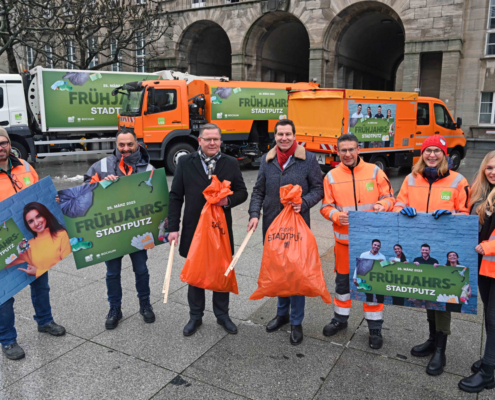 7 Personen stehen vor drei Fahrzeugen und halten stadtputzmaterial und Schilder in der Hand