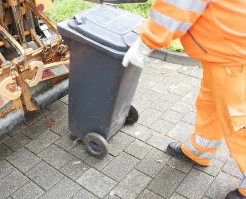 Eine Mülltonne wird zur Schüttung geschoben
