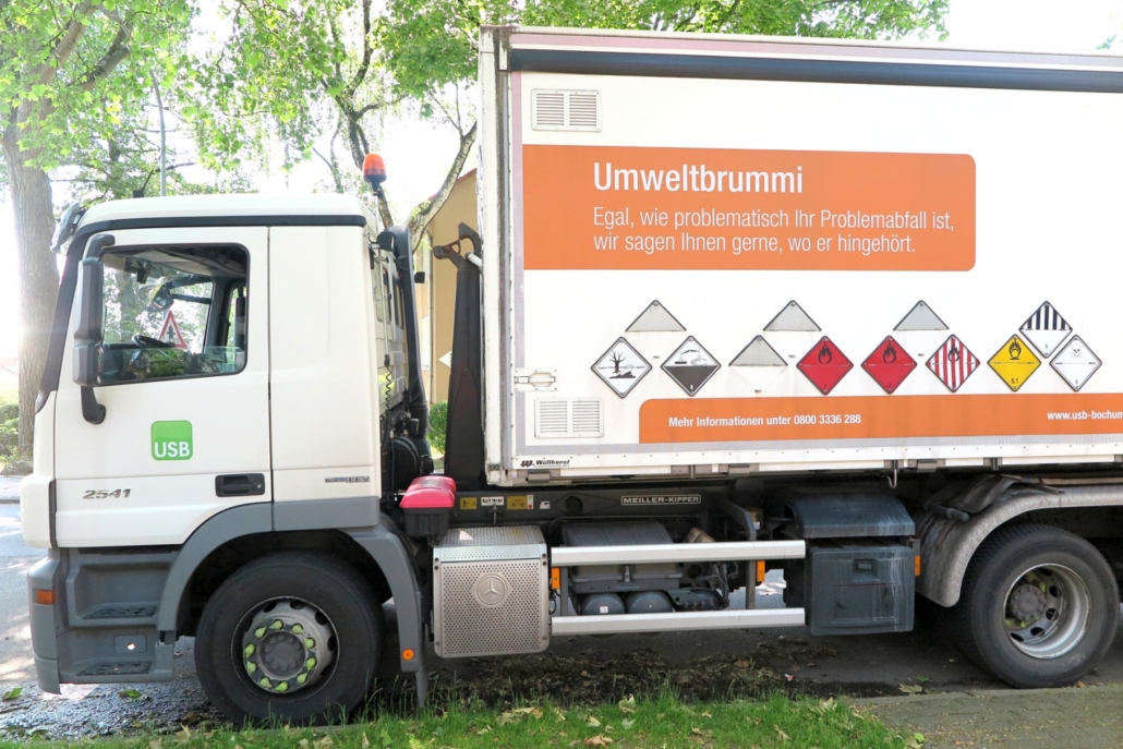 Ein weißer LKW mit der Aufschrift Umweltbrummi und mehreren Warnzeichen.