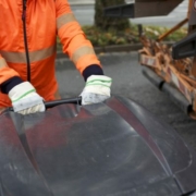 Die Hände eines Müllmannes greifen eine Mülltonne