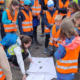 Kinder in orange gekleidet schauen sich pflanzen und Kleintiere an, die ihnen gezeigt werden