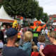 Ein Mann gekleidet als Mülleimer wird von Außenstehenden applaudiert