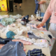 Auf einem Tisch liegen Babyklamotten zwei Frauen schauen sich die Sachen an
