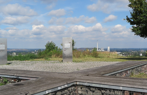 eine Kreuzförmige Holzbank auf der Spitze des Tippels Berges mit einer Aussicht über Bochum