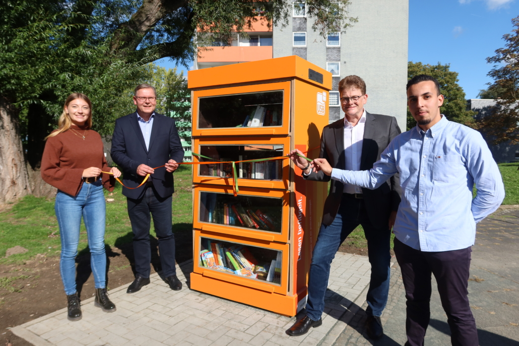 Drei Männer und eine Frau eröffnen einen neuen Bücherschrank