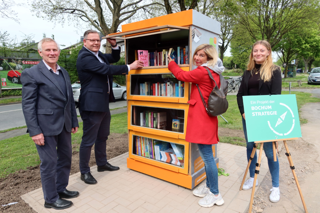 Zwei Männer und zwei Frauen präsentieren einen Bücherschrank