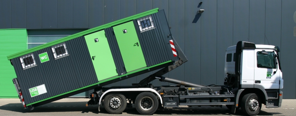 Ein weißes Fahrzeug liefert einen Toiletten-Container ab
