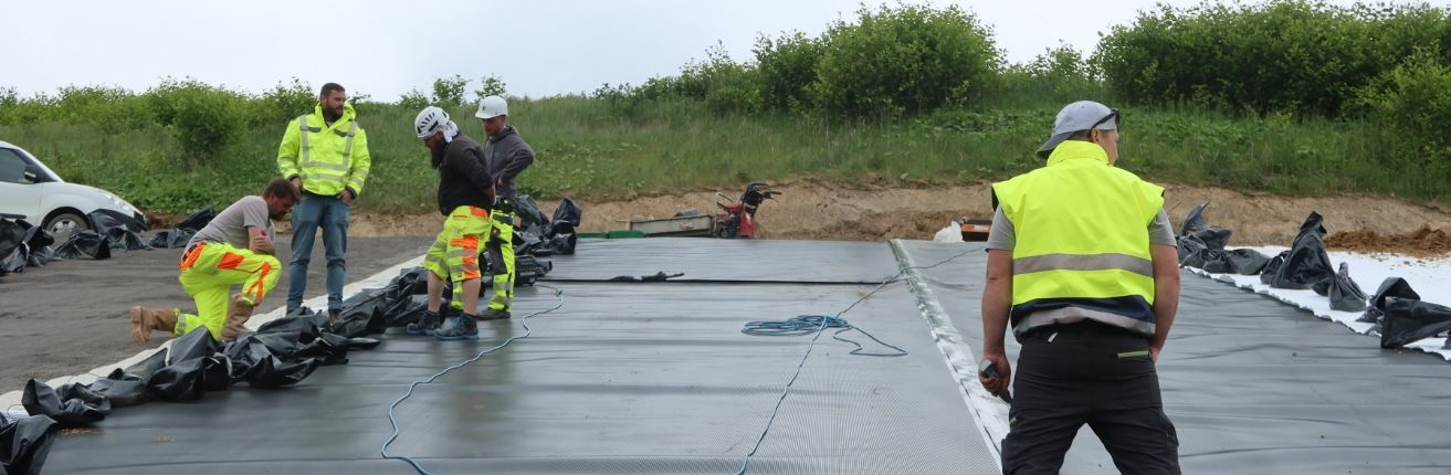 Arbeiter stehen in gelben Anziehsachen auf einer Baufläche