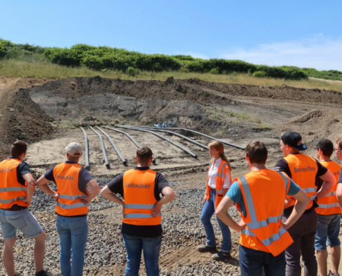 eine Menschengruppe schaut sich die Fortschritte auf einer Baustelle an
